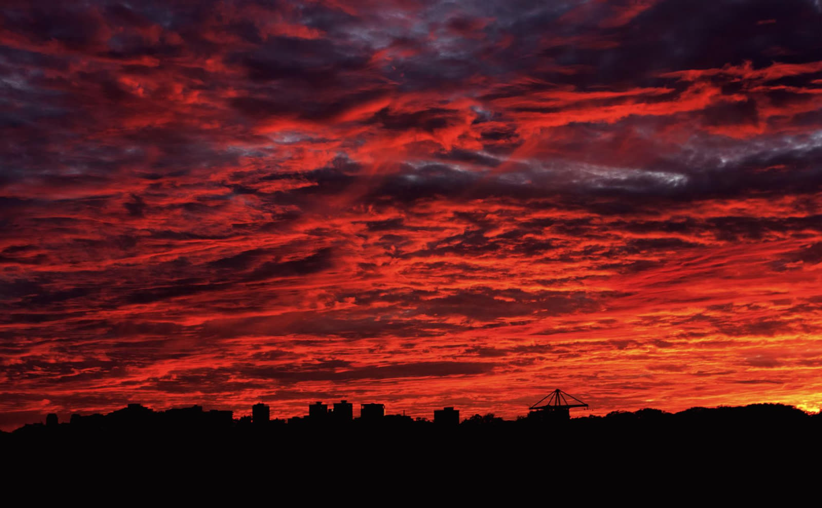 Burning red sunset sky over a dark city skyline